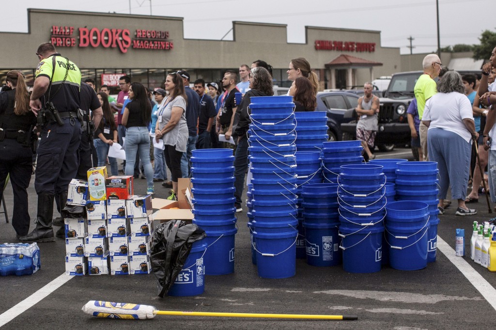 Voluntarios se reúnen en el estacionamiento de un centro comercial a ayudar para los afectados por las inundaciones en San Marcos, Texas