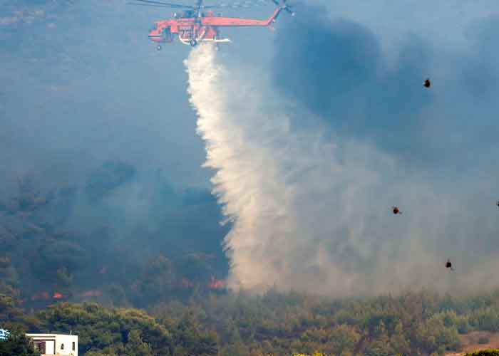 Helicóptero bombero rocía agua en un incendio descontrolado 