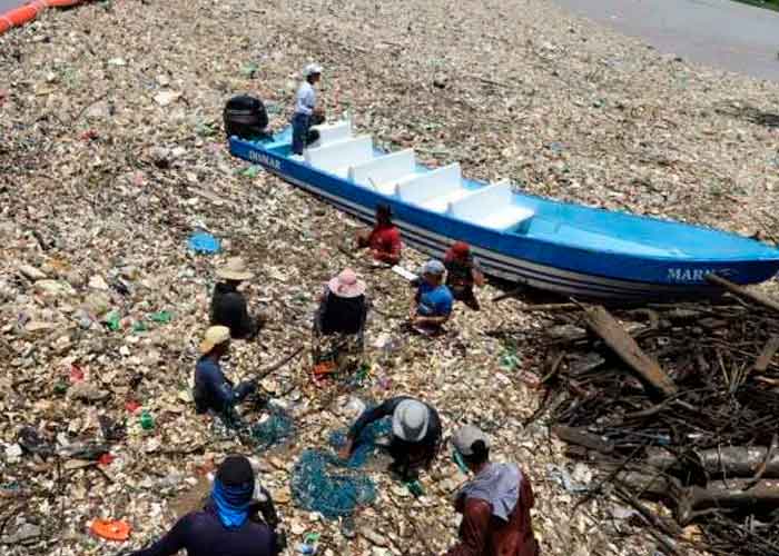 Varias personas en medios de toneladas de basura en la playa