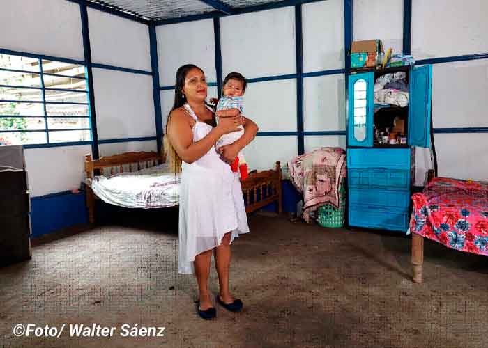 Una mujer junto a su bebé reciben su nueva viviendas digna 