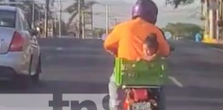 Momento en que un motorizado lleva a una niña en una cajilla, a bordo de una moto, en Managua